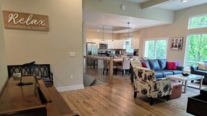 A spacious living area with a dining table, a sofa, and a kitchen in the background.