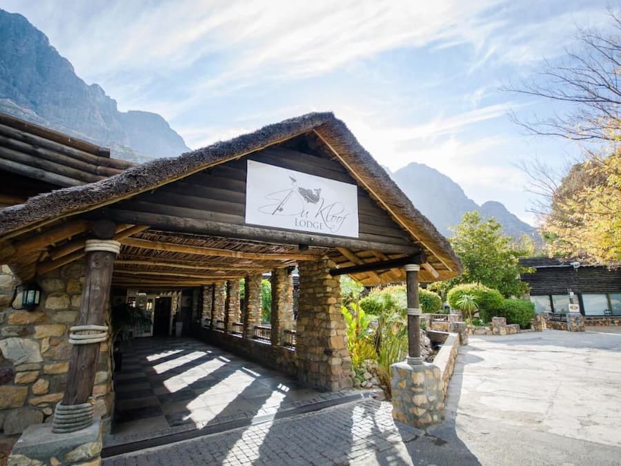 Entrada de un albergue con fachada de piedra, vigas de madera y un letrero.