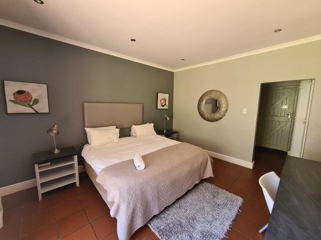 Quarto bem arrumado com uma cama grande, mesas de cabeceira, um espelho redondo e obras de arte nas paredes.