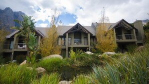 A hotel with multiple buildings, a pond, and mountains in the background.