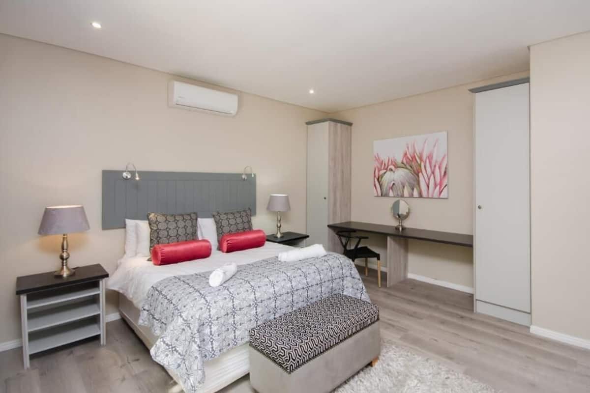 Une chambre à coucher comprenant un lit, des tables de chevet, un bureau et une armoire.