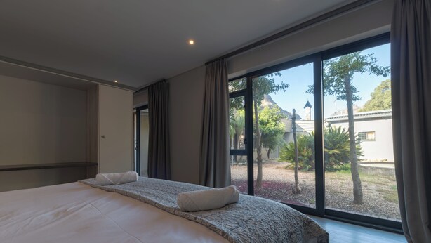 Une chambre d’hôtel moderne avec un grand lit, une vue sur l’extérieur et une fenêtre avec des rideaux.