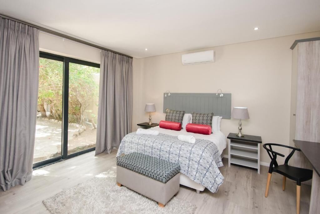 A modern bedroom with a large bed, bedside tables, a desk, and a chair.