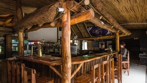 Un coin bar rustique, avec des meubles en bois et un toit de chaume.