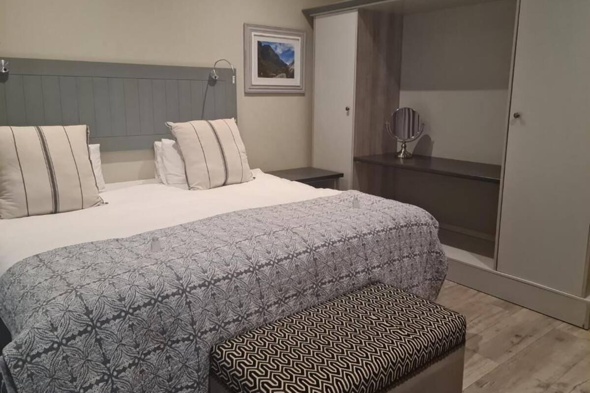 Une chambre à coucher comprenant un lit, une table de chevet, un banc, une armoire et un tableau encadré accroché au mur.