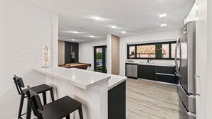 Una cocina moderna con una isla central, taburetes de bar y un refrigerador grande.