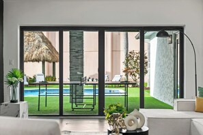 Un intérieur moderne avec une grande porte-fenêtre coulissante donnant sur un espace piscine extérieur.