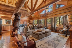 A log cabin interior with a dining area, sofa, and a large wooden sculpture.