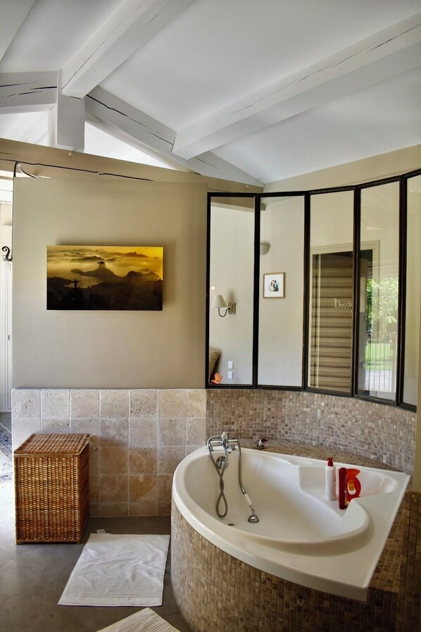 A modern bathroom with a freestanding bathtub, a large mirror, and a painting of a sunset.