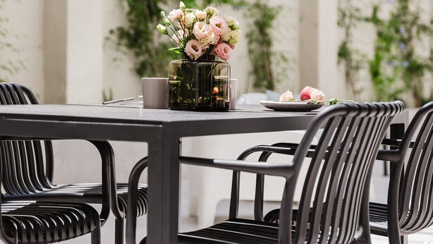 A dining area with a table set for two, featuring a vase of flowers and a plate of food.