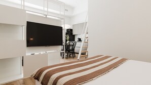 A modern, minimalist bedroom with a large bed, a flat-screen TV mounted on the wall, and a dining area with a table and chairs.