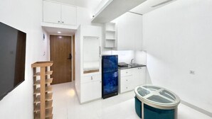 A modern kitchen with white cabinets, a blue refrigerator, and a glass trash bin. - 300sqft 5 Studio Gym & Pool Access (Dhaka)