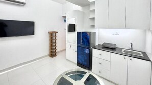 A modern kitchen with white cabinets, a built-in refrigerator, a black countertop, and a wall-mounted TV. - 300sqft 5 Studio Gym & Pool Access (Dhaka)