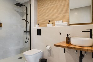 A modern bathroom with a shower, toilet, and sink.