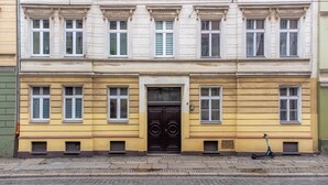A multi-story building with a central black door, multiple windows, and a scooter parked outside. - Apartamenty Sun & Snow Szczytnicka (Wroclaw)
