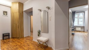 A hallway with wooden flooring, a white bench, a large mirror, and a plant. - Apartamenty Sun & Snow Szczytnicka (Wroclaw)