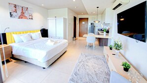 Une chambre d’hôtel moderne équipée d’un grand lit, d’un bureau, d’une télévision et d’une kitchenette.