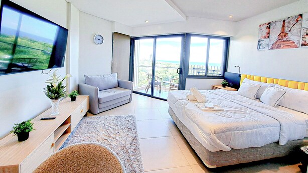 Une chambre moderne avec un lit, un canapé, une télévision et un balcon offrant une vue agréable.