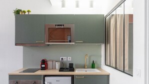 A compact kitchen with a built-in oven, a sink, and a small refrigerator.