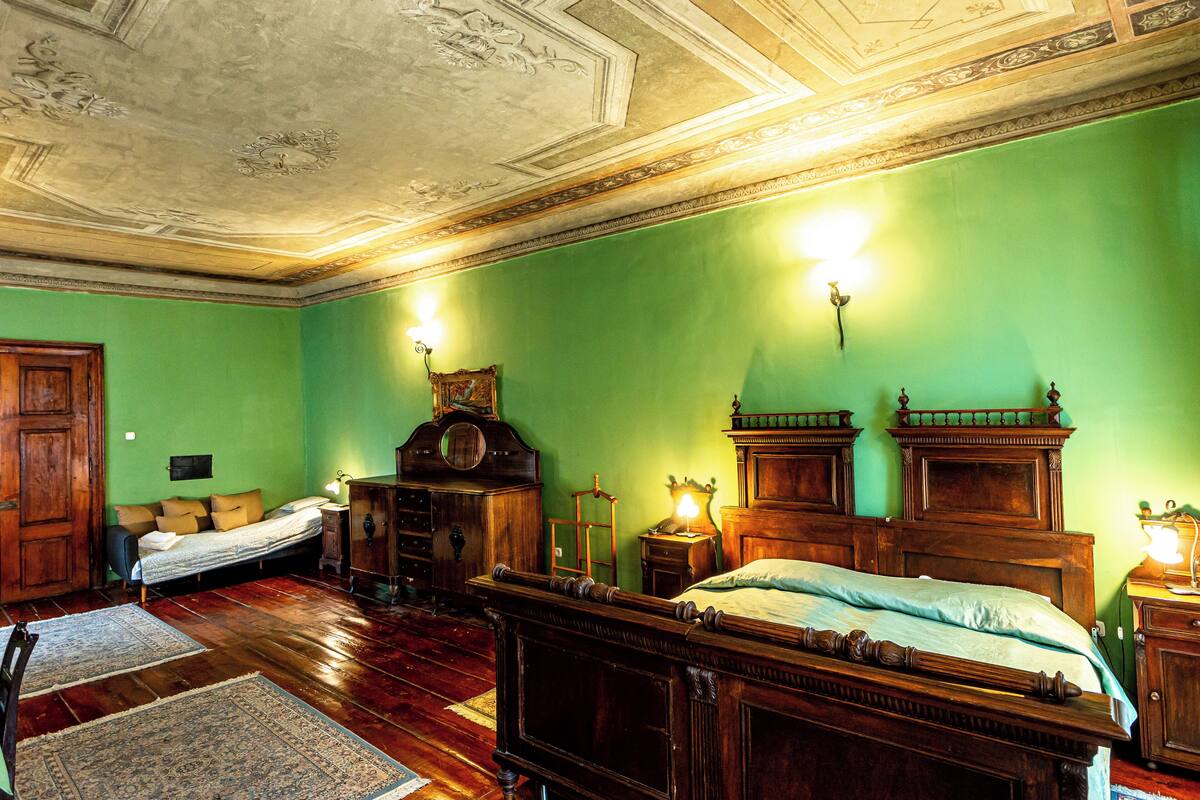 Une pièce comprenant un grand lit en bois, une commode en bois, une table de chevet en bois, une chaise en bois et un bureau en bois.