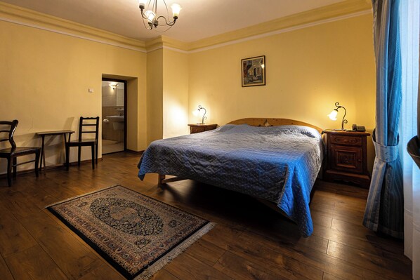 Een slaapkamer met een bed, een bureau, een stoel, een nachtkastje en een vloerkleed.