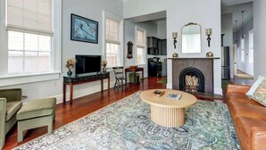 A living room with a fireplace, a television, and a large window.