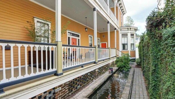 A building with a covered porch, a brick water feature, and a hedge.
