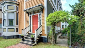 A corner building with a red door, a small front porch, and a brick pathway leading to the entrance.