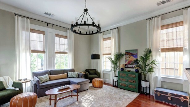 A spacious living room with a sofa, ottoman, and a green chest of drawers. - The Koi Escape, Victorian | Upper Porch | Parking (Savannah)