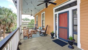 A covered porch with wooden flooring, ceiling fans, string lights, and outdoor furniture. - The Koi Escape, Victorian | Upper Porch | Parking (Savannah)