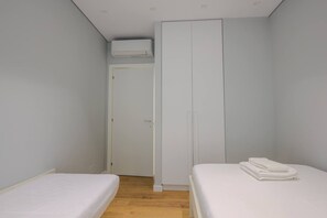 Una camera da letto con due letti singoli, un armadio e una porta con un asciugamano bianco a destra.