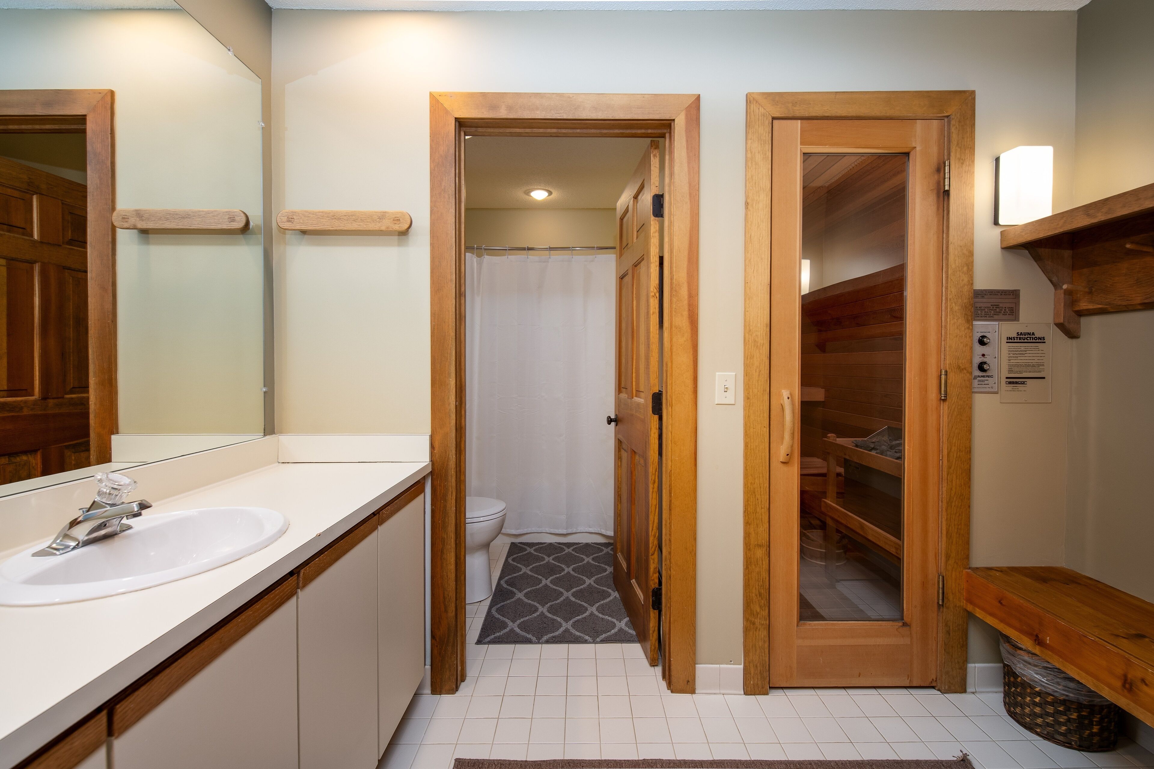 A bathroom with a wooden door, a white sink, and a shower area.