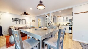 Una cocina moderna con armarios blancos, una isla central y un comedor con mesa y sillas.