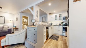 Una cocina moderna con armarios blancos, electrodomésticos de acero inoxidable y piso de madera.