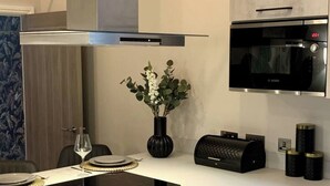 A modern kitchen with a built-in oven, a black Bosch microwave, and a black toaster. - Historic 5* Tudor Residence: Penthouse (Manchester)