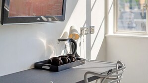 A modern room with a cityscape TV, a coffee maker, and a tray with mugs. - Roland House - Deluxe Studio (London)