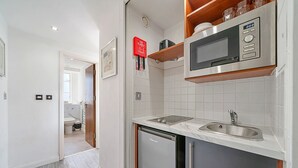 A compact kitchen with a built-in microwave, a sink, and a dishwasher. - Roland House - Deluxe Studio (London)