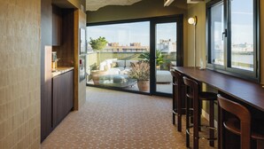 A modern kitchen with a large window, a dining area with bar stools, and a view of the cityscape. - Atipico Madrid (Madrid)
