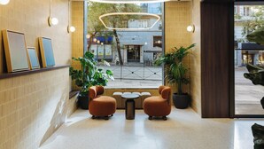 A modern lobby with a seating area, potted plants, and framed pictures on the wall. - Atipico Madrid (Madrid)
