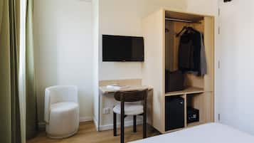 Camera d'albergo compatta con un letto, una scrivania con una sedia, una televisione e un armadio.