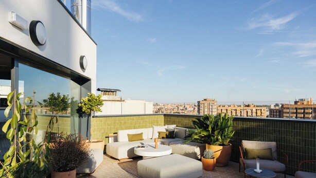 A rooftop terrace with a sofa set, a round table, and potted plants. - Atipico Madrid (Madrid)