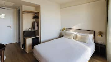 A hotel room with a bed, bedside tables, a wardrobe, and a desk with a chair.