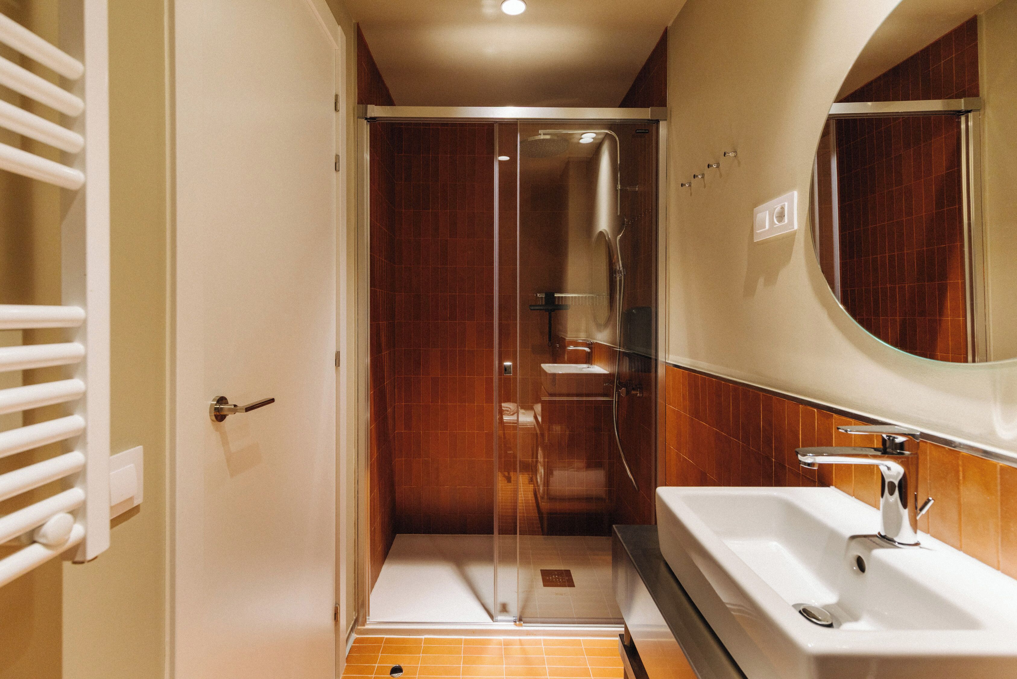 A bathroom with a glass-enclosed shower, a white sink, and a mirror above it.