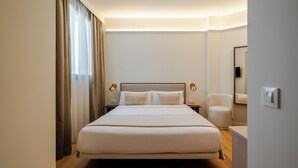 A hotel room with a large bed, bedside lamps, a chair, and a mirror. - Atipico Madrid (Madrid)