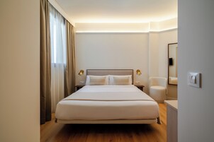 Une chambre d’hôtel avec un grand lit, des lampes de chevet, une chaise et un miroir.