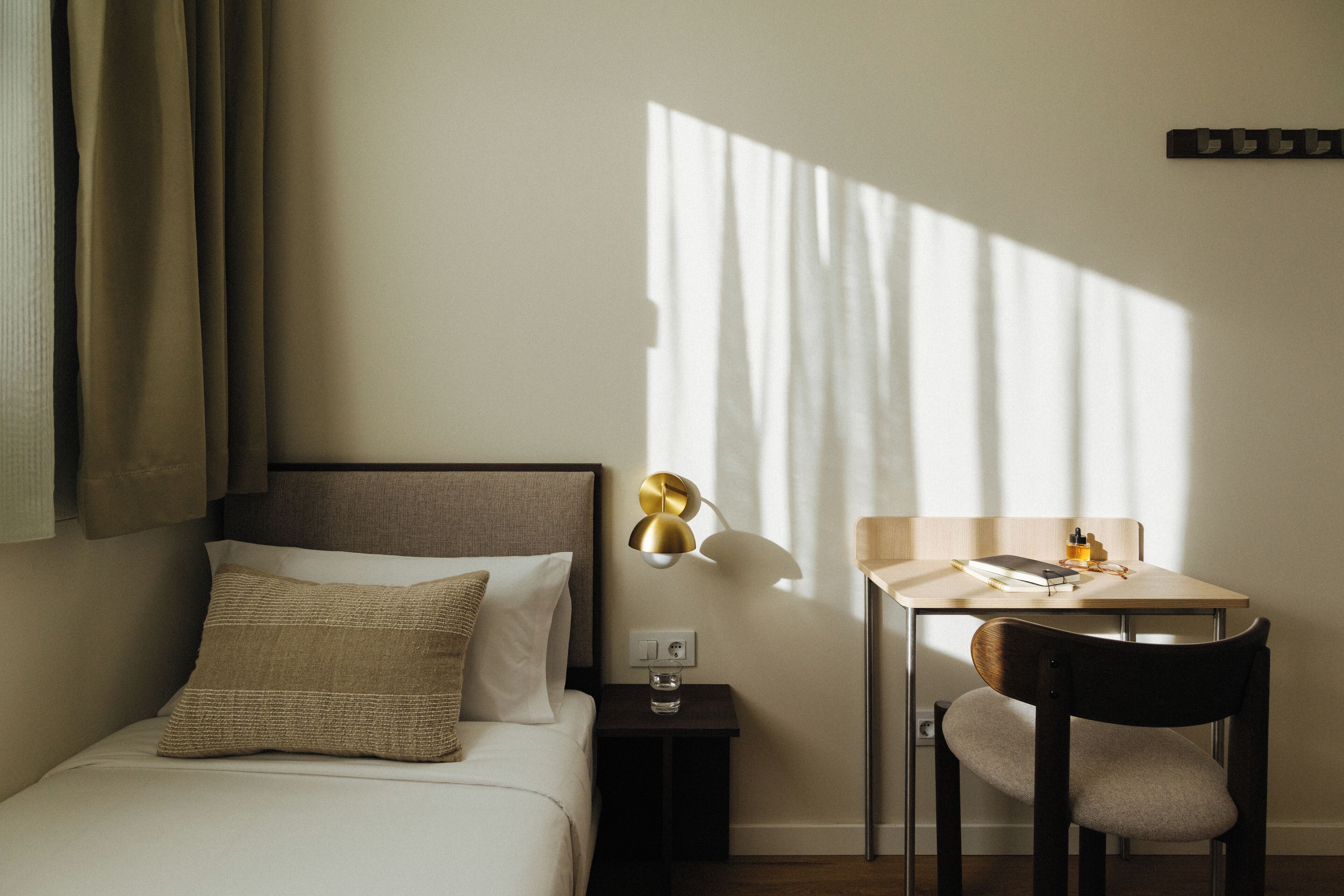 A neatly arranged bedroom with a bed, bedside table, lamp, and a chair.