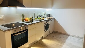 A compact kitchen with a built-in oven, a washing machine, and a microwave. - Charming Rural House (Arona)