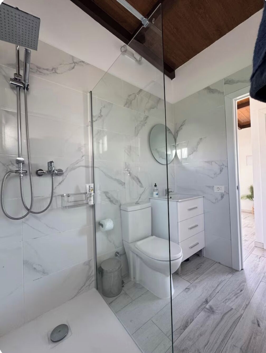 Een moderne badkamer met een douche met glazen wand, een toilet en een wastafel met lades.