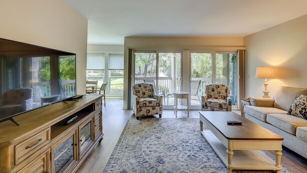 A living room with a television, sofa, coffee table, and patterned rug. - Sunset Rentals | Lighthouse Tennis 2387 (Hilton Head Island)