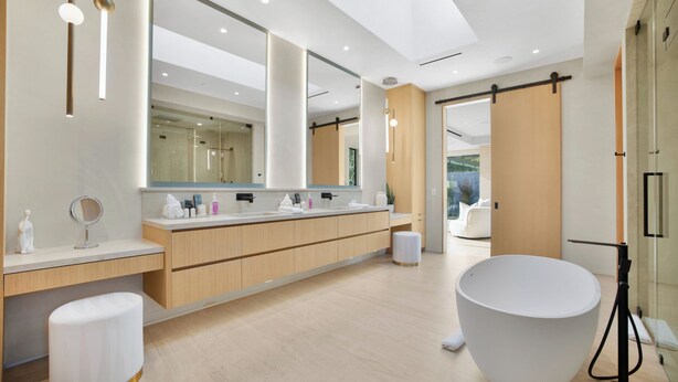 Une salle de bain moderne avec un grand miroir, une baignoire sur pieds et une lucarne.